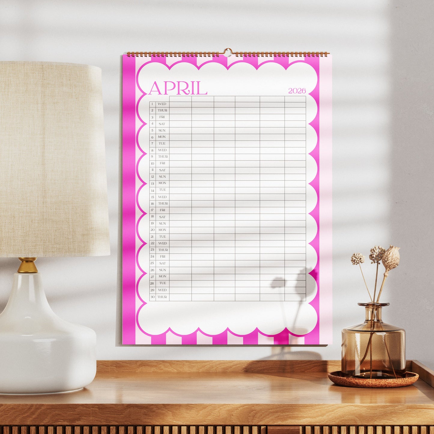 Wall A3 Family calendar for April on a wooden surface with a lamp and decorative items.