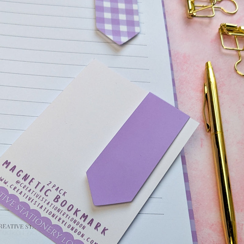 Purple magnetic bookmarks on a notebook with a gold pen