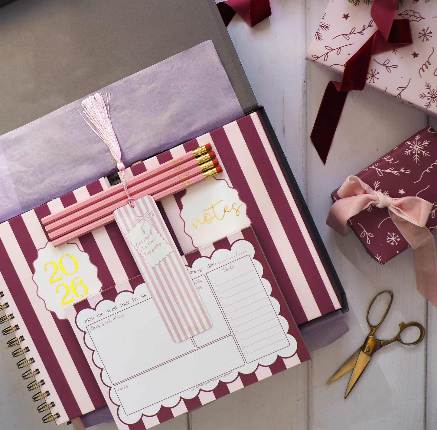 Decorative notebook & 2026 diary planner with notepad with striped cover, ribbons, and a wreath on a white surface.