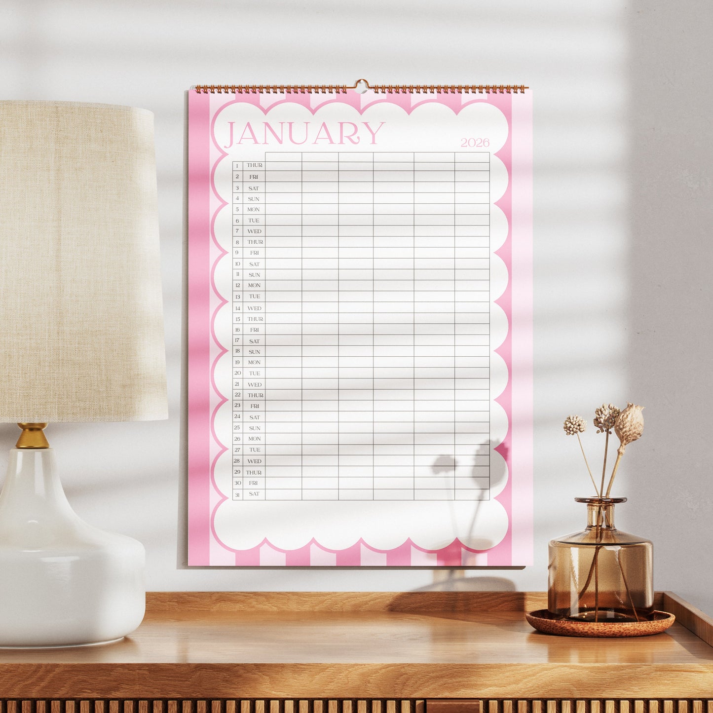 A3 Family Wall calendar for January on a wooden surface with a lamp and decorative items.