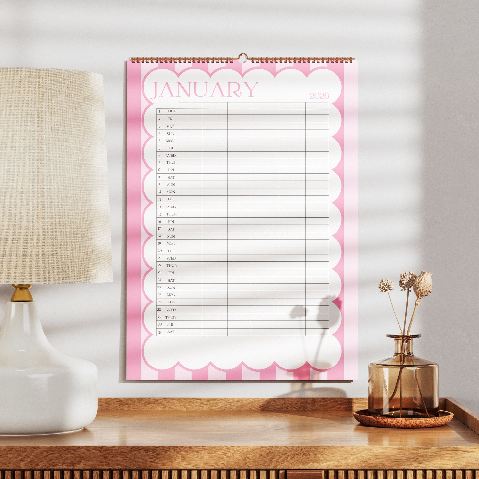 A3 Family Wall calendar for January on a wooden surface with a lamp and decorative items.