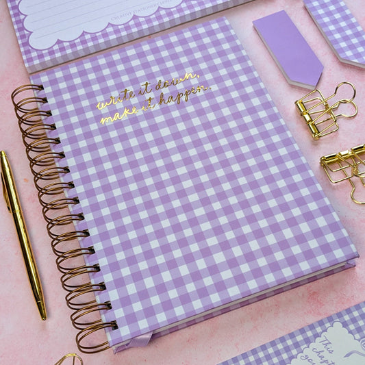 Purple checkered notebook with gold text on a pink background
