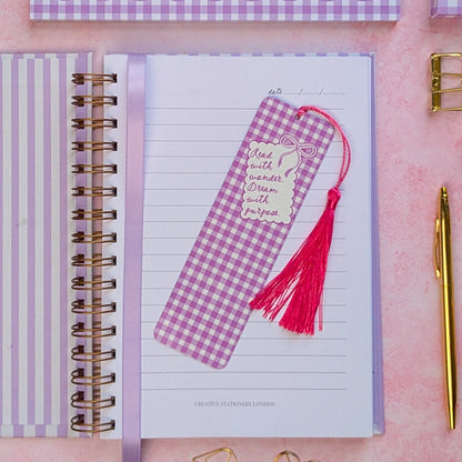 Notebook with a pink and purple checkered bookmark on a pink surface