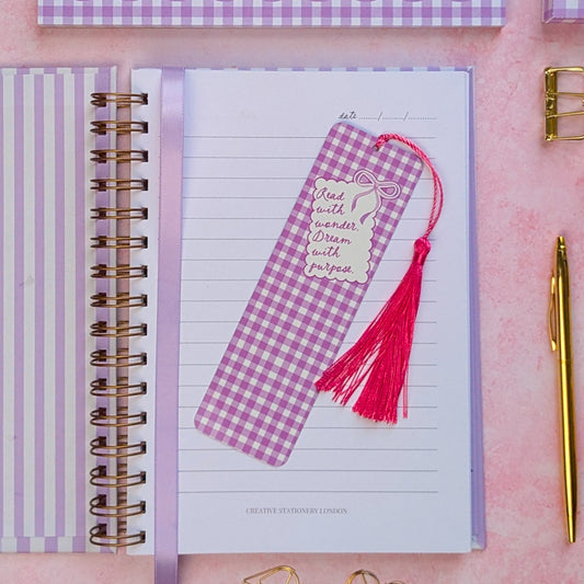 Notebook with a pink and purple checkered bookmark on a pink surface