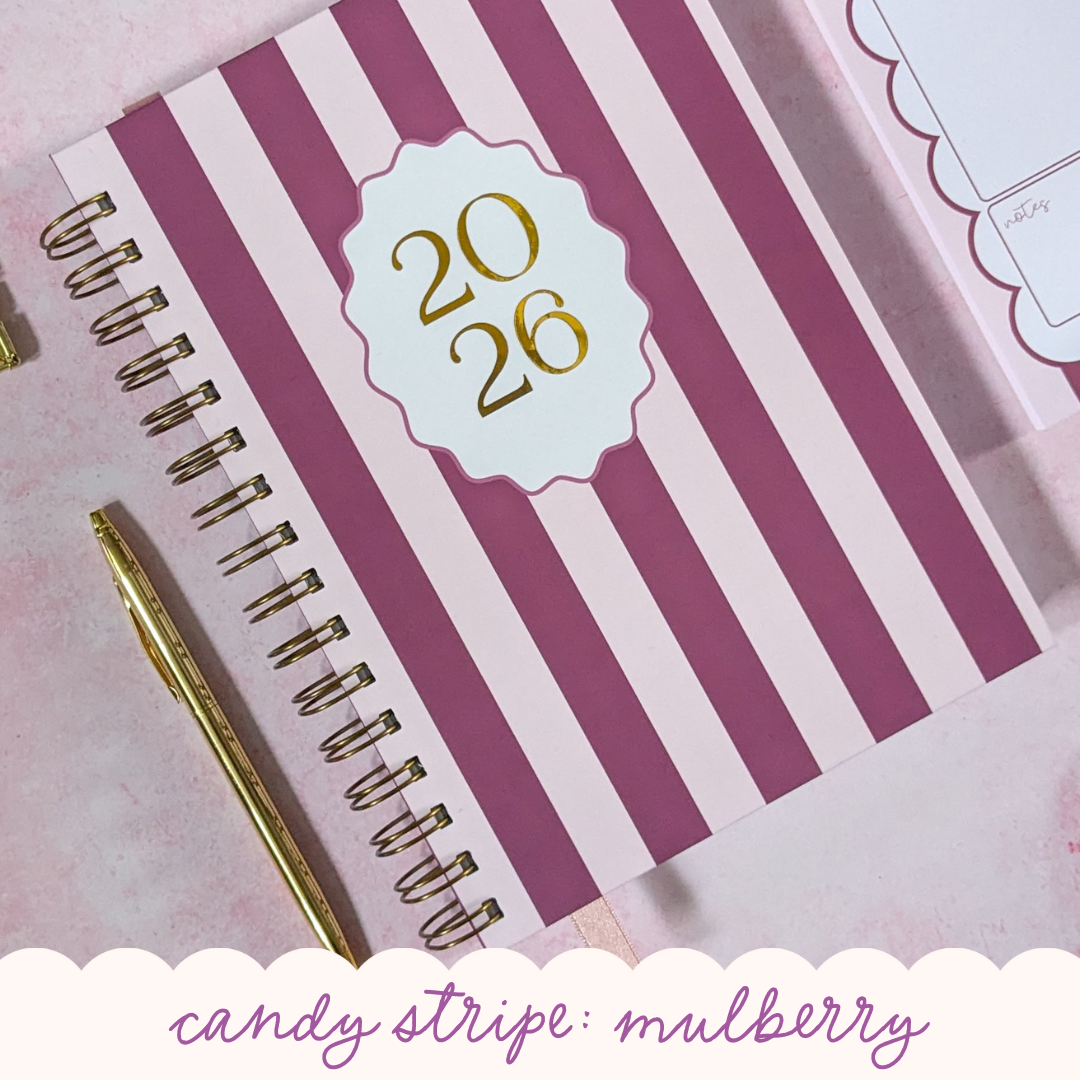 Spiral-bound notebook with candy stripe mulberry design and gold pen on a pink background