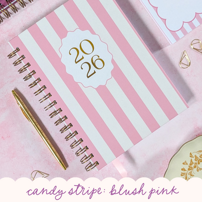 Pink and white striped planner with gold pen on a matching background