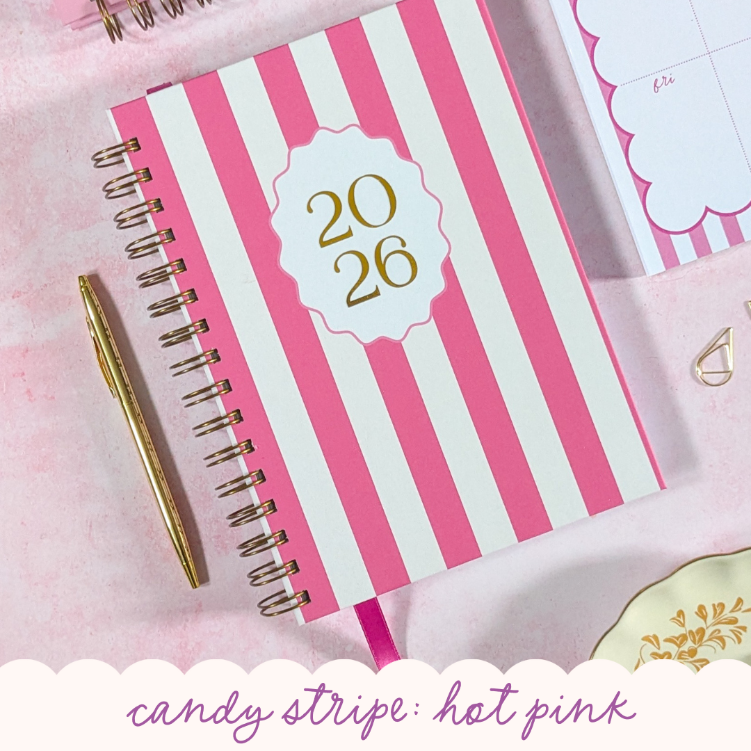 Pink and white striped planner with gold accents on a pink background
