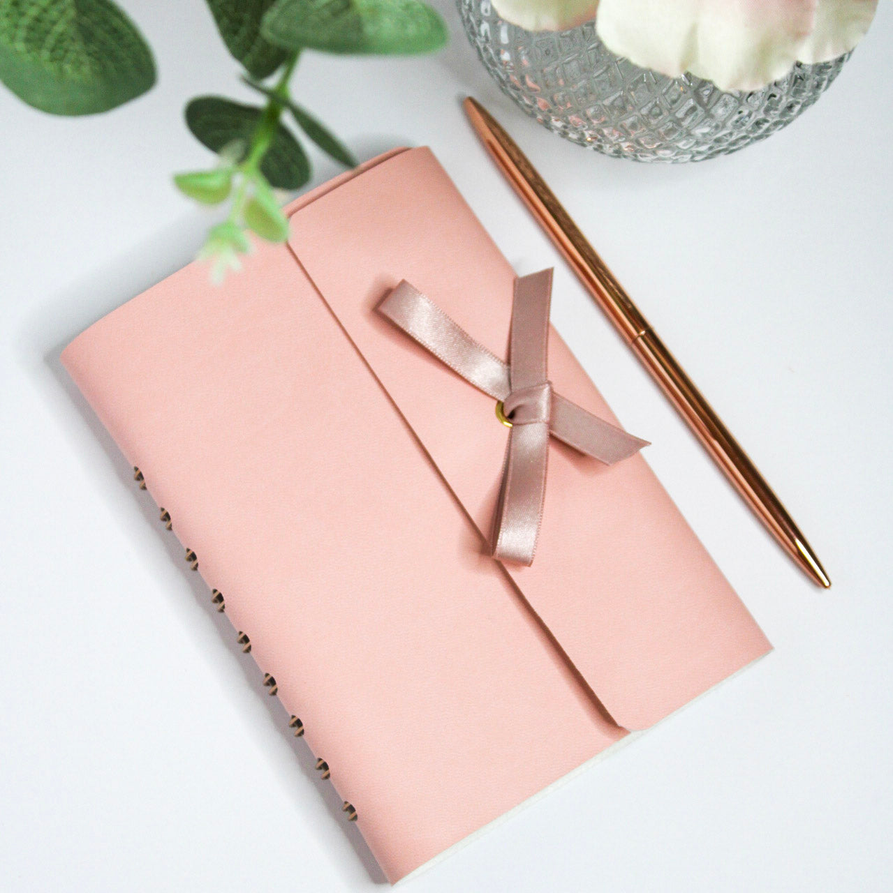 Blush Pink Vegan Leather Notebook with rose gold ribbon tied in a bow.